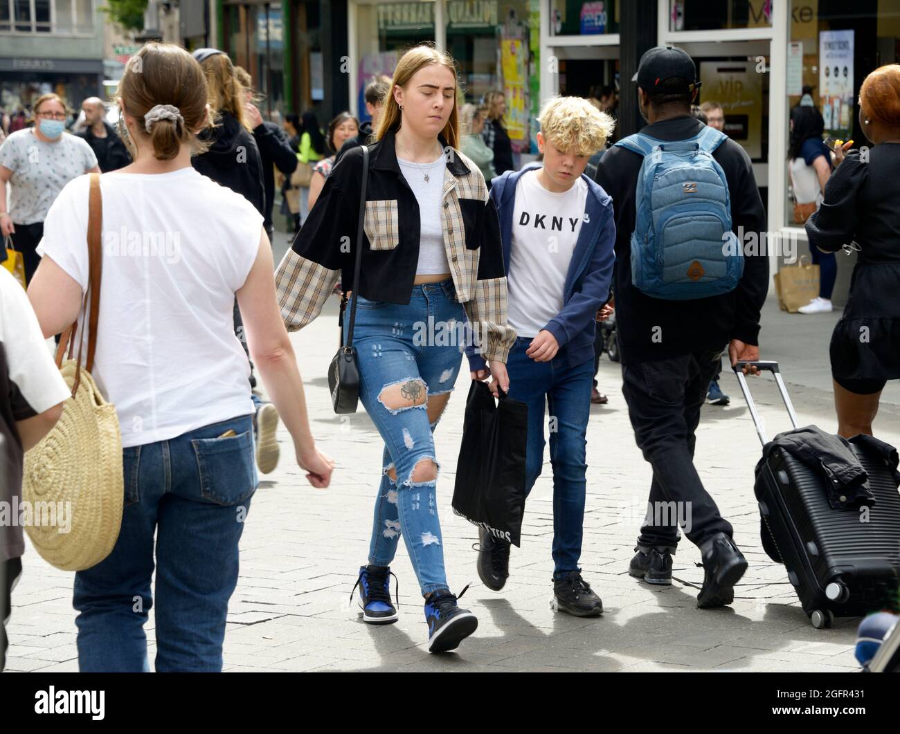 Giovani fuori shopping, jeans strappati. Foto Stock
