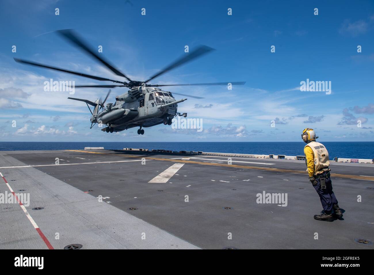 MAR DELLE FILIPPINE (ago. 25, 2021) Aviation Boatswain’s Mate (Handling) terza classe Steven Crisologo, da Manila, Filippine, assegnato alla nave d’assalto anfibio dispiegata in avanti USS America (LHA 6), segnala un elicottero CH-53E Super Stallion dalla 31esima unità di spedizione navale (MEU) di atterrare sul ponte di volo della nave durante le operazioni di volo. L'America e l'elemento di combattimento aereo del 31 MEU mantengono un piano strategico pronto per una varietà di missioni. L'America, ammiraglia dell'America Expeditionary Strike Group, insieme al 31 MEU, sta operando nell'area della settima flotta degli Stati Uniti di responsabilità Foto Stock