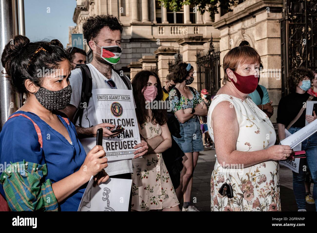 Dublino, Irlanda. 26 agosto 2021. Un manifestante tiene un cartello durante la manifestazione.decine di persone si sono radunate di fronte all'edificio del parlamento irlandese, Leinster House, per chiedere al governo irlandese di accogliere più rifugiati afghani. United Against Racism ha organizzato la protesta, mentre altri partiti ed organizzazioni come la gente prima del profitto, ROSA, e le Chéile erano anche presenti. I manifestanti hanno sostenuto che da quando il governo irlandese aveva precedentemente permesso ai militari statunitensi di utilizzare l’aeroporto di Shannon, l’Irlanda non dovrebbe più rifiutarsi di accettare i rifugiati. Credit: SOPA Images Limited/Alamy Live News Foto Stock