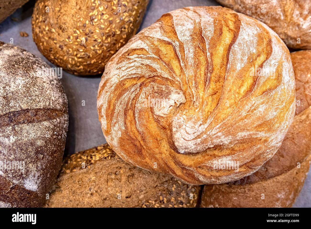 Pagnotta rotonda di pane su sfondo di diversi pani di pane. Sfondo vista dall'alto raccolta pane. Foto Stock