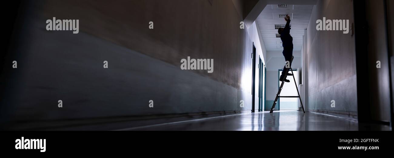 Riparazione uomo su scala in Office fissaggio soffitto fissaggio Foto Stock