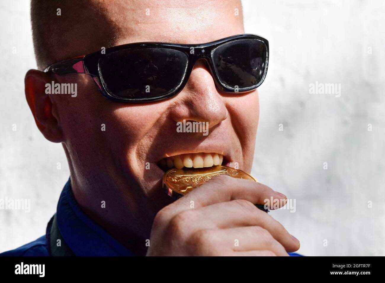 Oleksandr Mashchenko, campione paralimpico della squadra di nuoto Ucraina, si vede mordere la sua medaglia d'oro olimpica durante la sessione fotografica. Foto Stock