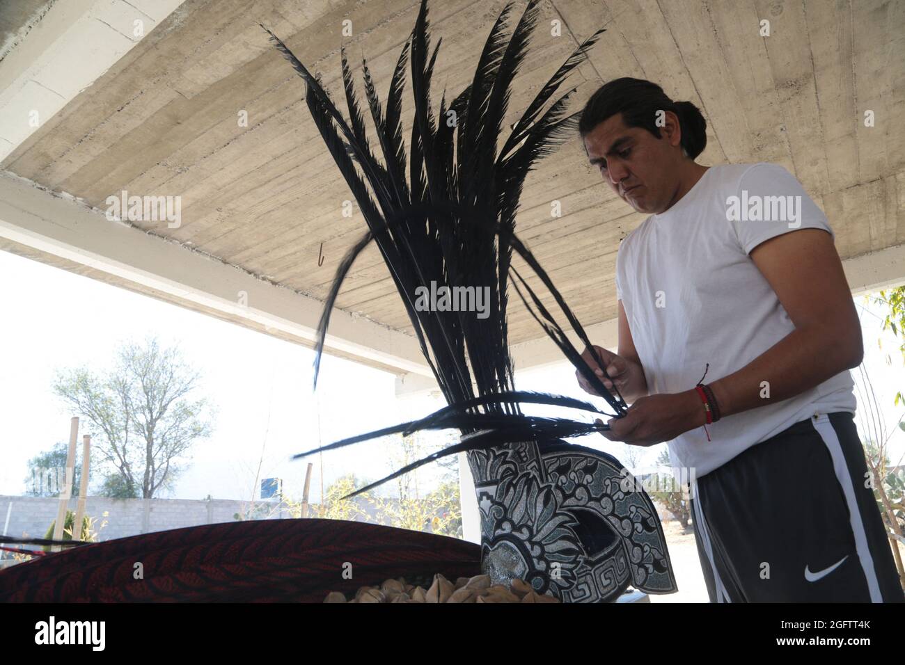 Un uomo mette le piume in un pennacchio prima vestito come guerriero azteco come parte di una cerimonia pre-ispanica nella zona archeologica. Teotihuacan, Messico, 26 agosto 2021. Foto di Ricardo Castelan/Eyepix/ABACAPRESS.COM Foto Stock