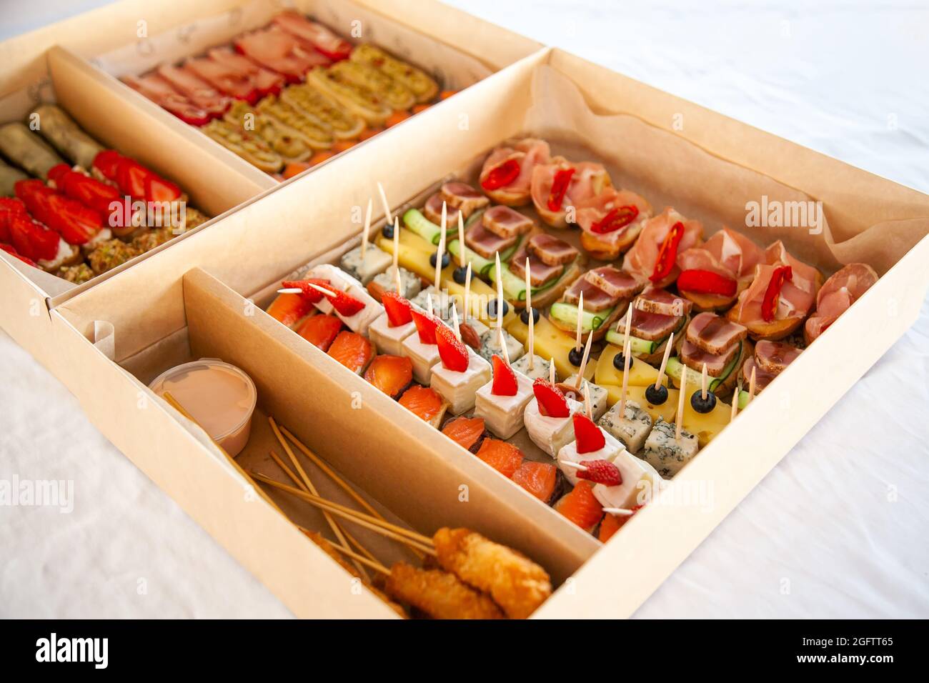 Scatola con piccoli sandwich, bruschetta con salumi, formaggi e frutti di  mare. Snack gourmet in cartone per catering a buffet per feste Foto stock -  Alamy