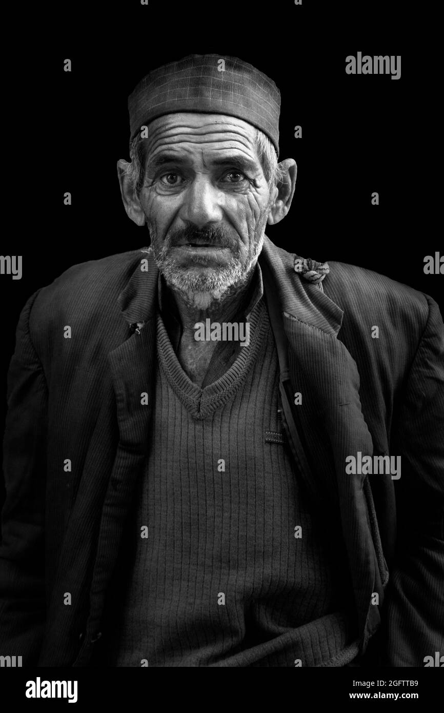 Ritratto di strada bianco e nero di un vecchio uomo con volto stropicciato che guarda verso la fotocamera con i suoi grandi occhi larghi Foto Stock