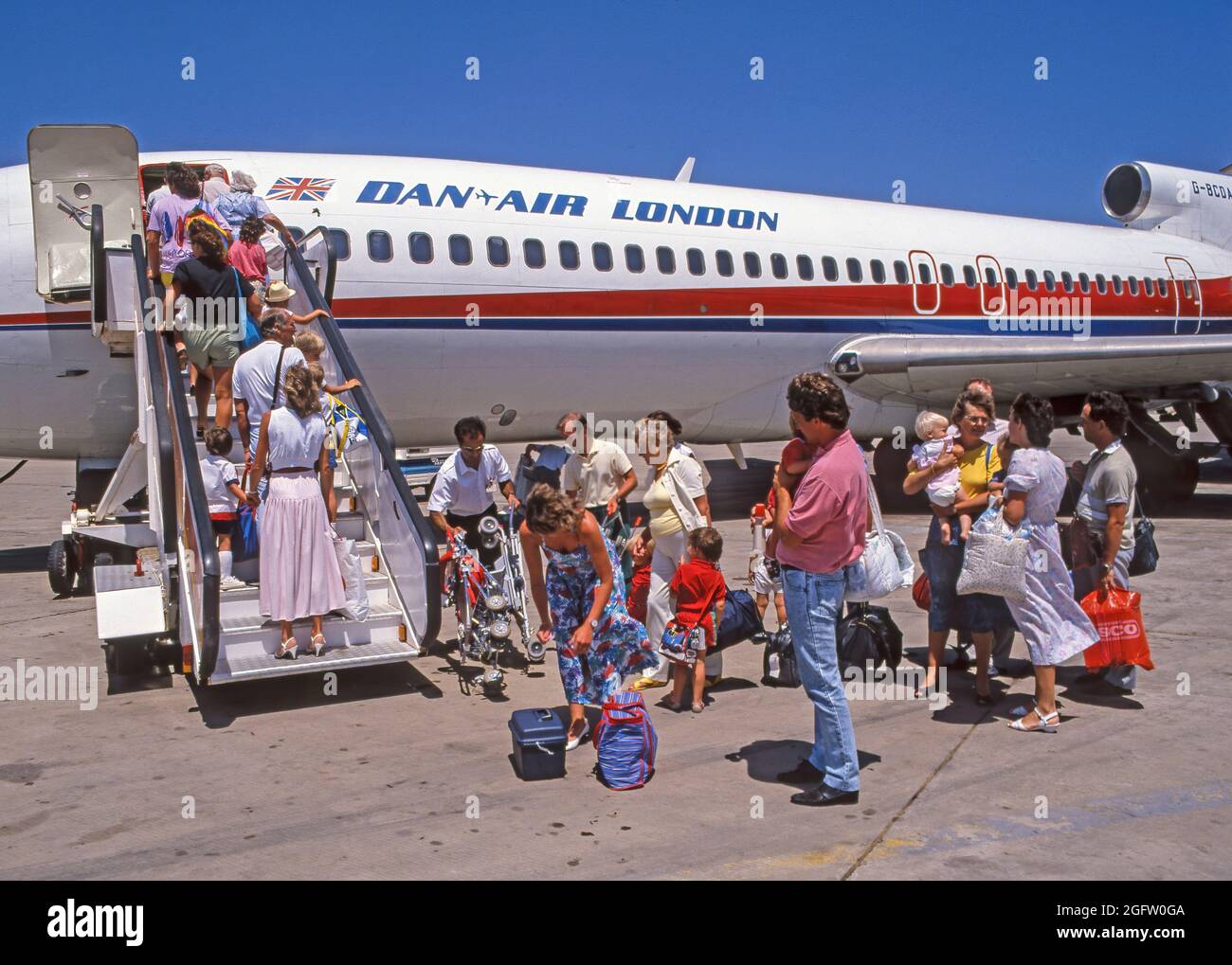 Famiglie come passeggeri a bordo di un volo Dan Air London a casa una scelta di vita di Mums e Dads a Mahón Menorca aeroporto in archivio ravvicinato 1991 vista del pacchetto vacanze estive di fine famiglia per famiglie che trasportano bambini piccoli e i bagagli a mano fanno la fila sotto il caldo sole spagnolo in una giornata di sole nel cielo azzurro del Mediterraneo a gradini di imbarco G-BCDA degli anni '1990 aereo jet in volo charter per tornare a casa con Boeing 727 tri jet in archivio immagine anni '80 Spagna Foto Stock