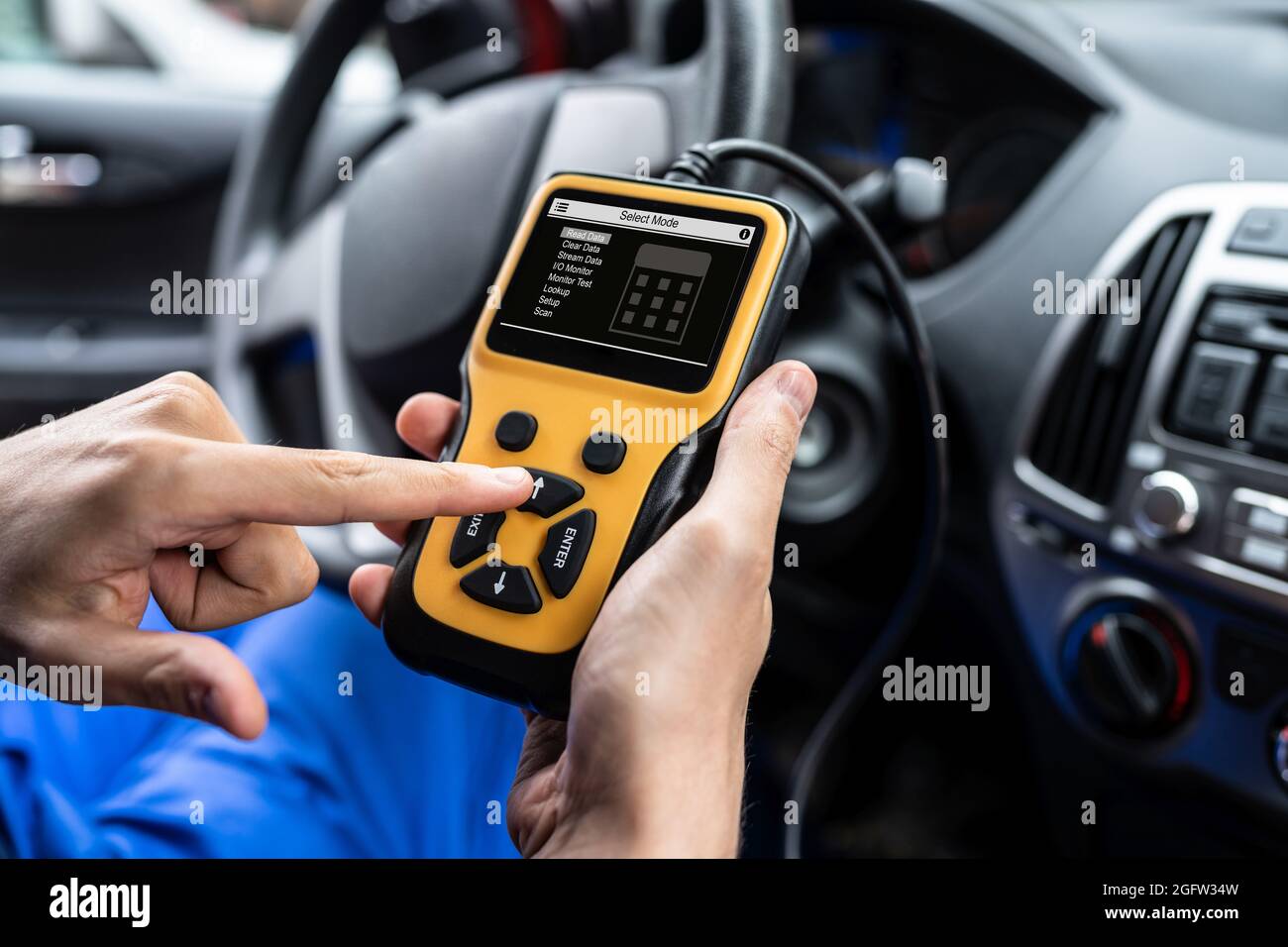 Tecnico del servizio di assistenza per automobili presso il negozio di riparazione utilizzando il dispositivo di diagnostica Foto Stock