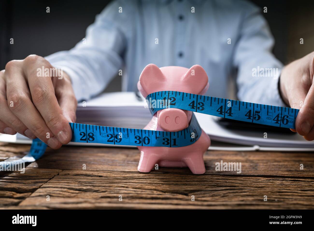 Misurazione di Piggy Bank a risparmio ridotto. Ridurre i contanti Foto Stock