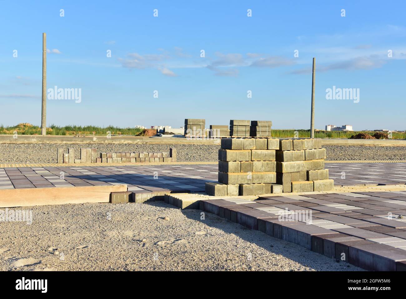 Posa di lastre di pavimentazione in cantiere. Processo di installazione di mattoni di pavimentazione nella zona pedonale della città. Spianando la sabbia per installare blo di calcestruzzo Foto Stock