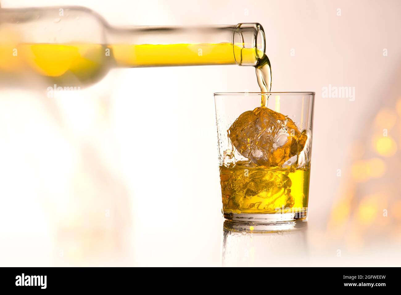 versare il whiskey in un bicchiere con cubetti di ghiaccio Foto Stock