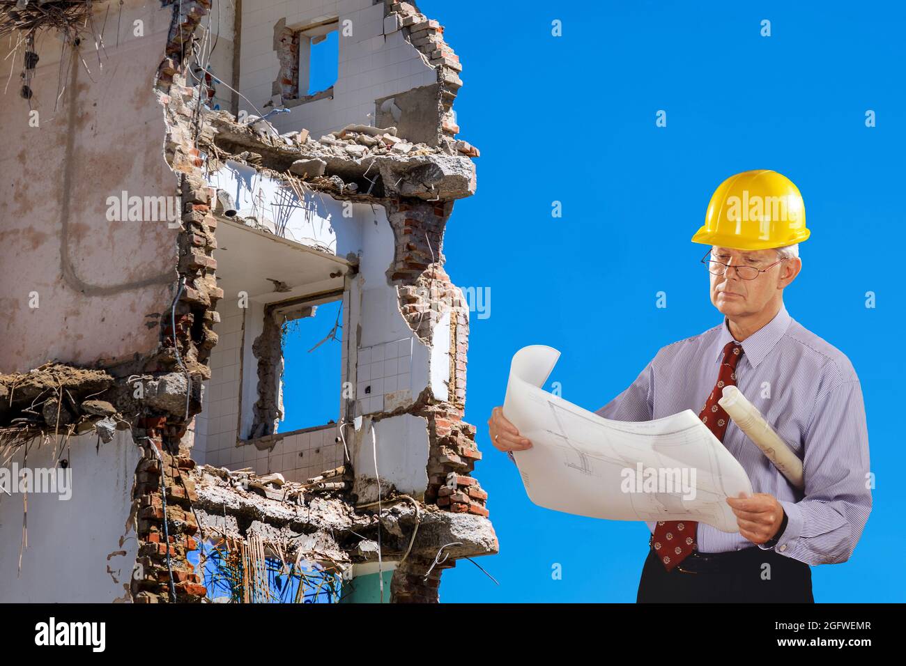 architetto con progetto di costruzione e elmetto, demolizione edificio in background Foto Stock