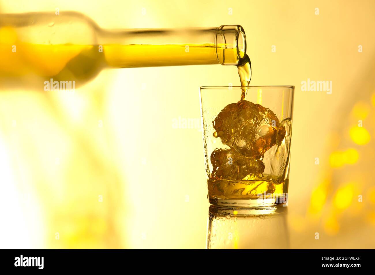 versare il whiskey in un bicchiere con cubetti di ghiaccio Foto Stock