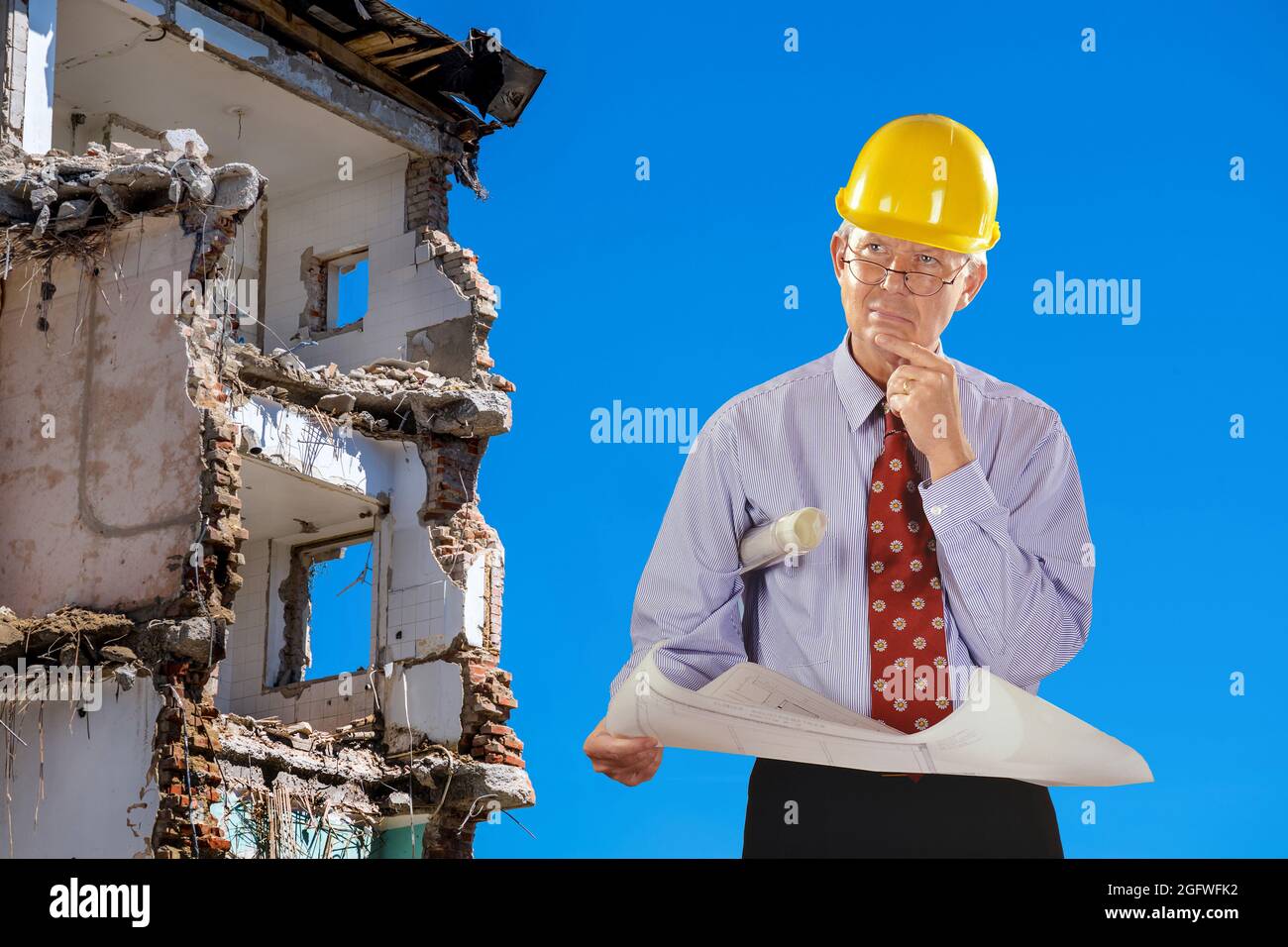 architetto con progetto di costruzione e elmetto, demolizione edificio in background Foto Stock