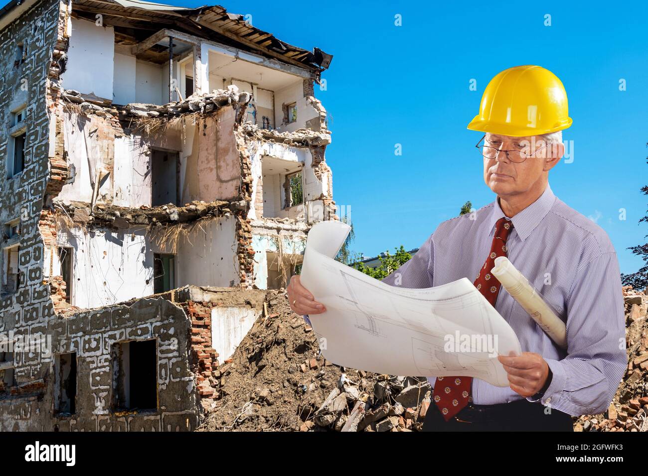 architetto con progetto di costruzione e elmetto, demolizione edificio in background Foto Stock