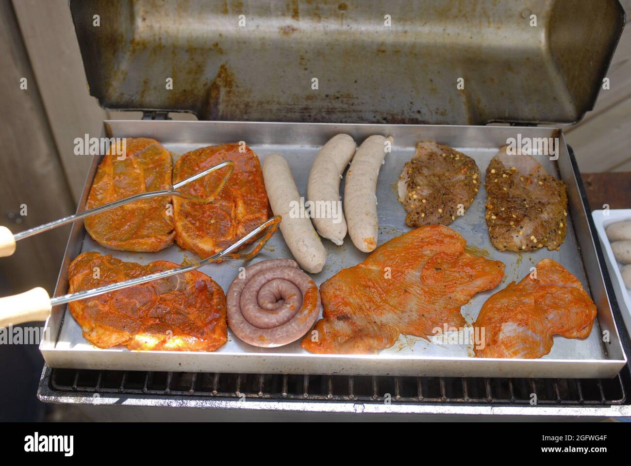 bratwurst e bistecche su una griglia a gas Foto Stock