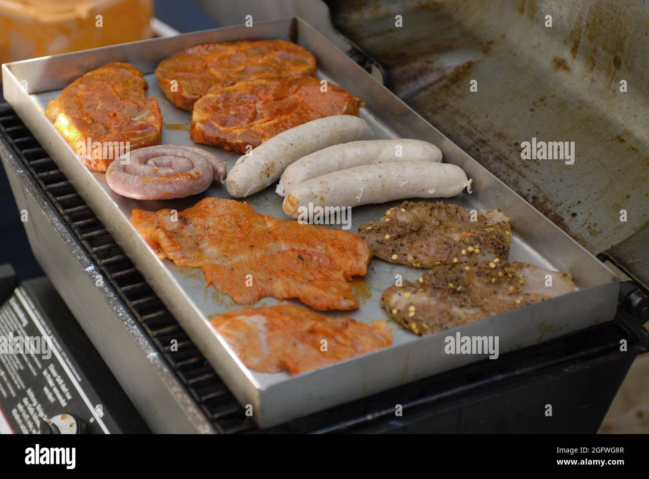 bratwurst e bistecche su una griglia a gas Foto Stock