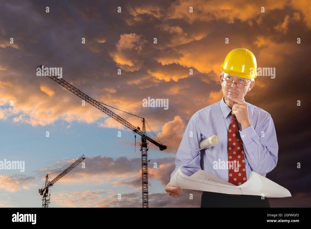 architetto con progetto di costruzione e elmetto, gru a torre sullo sfondo Foto Stock