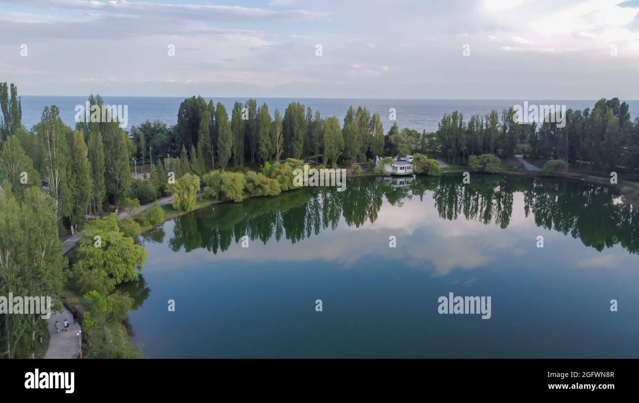 Idilliaco paesaggio estivo con laghetto con riflessi e alberi vicino al lago Issyk Kul, Kirghizistan. Foto Stock