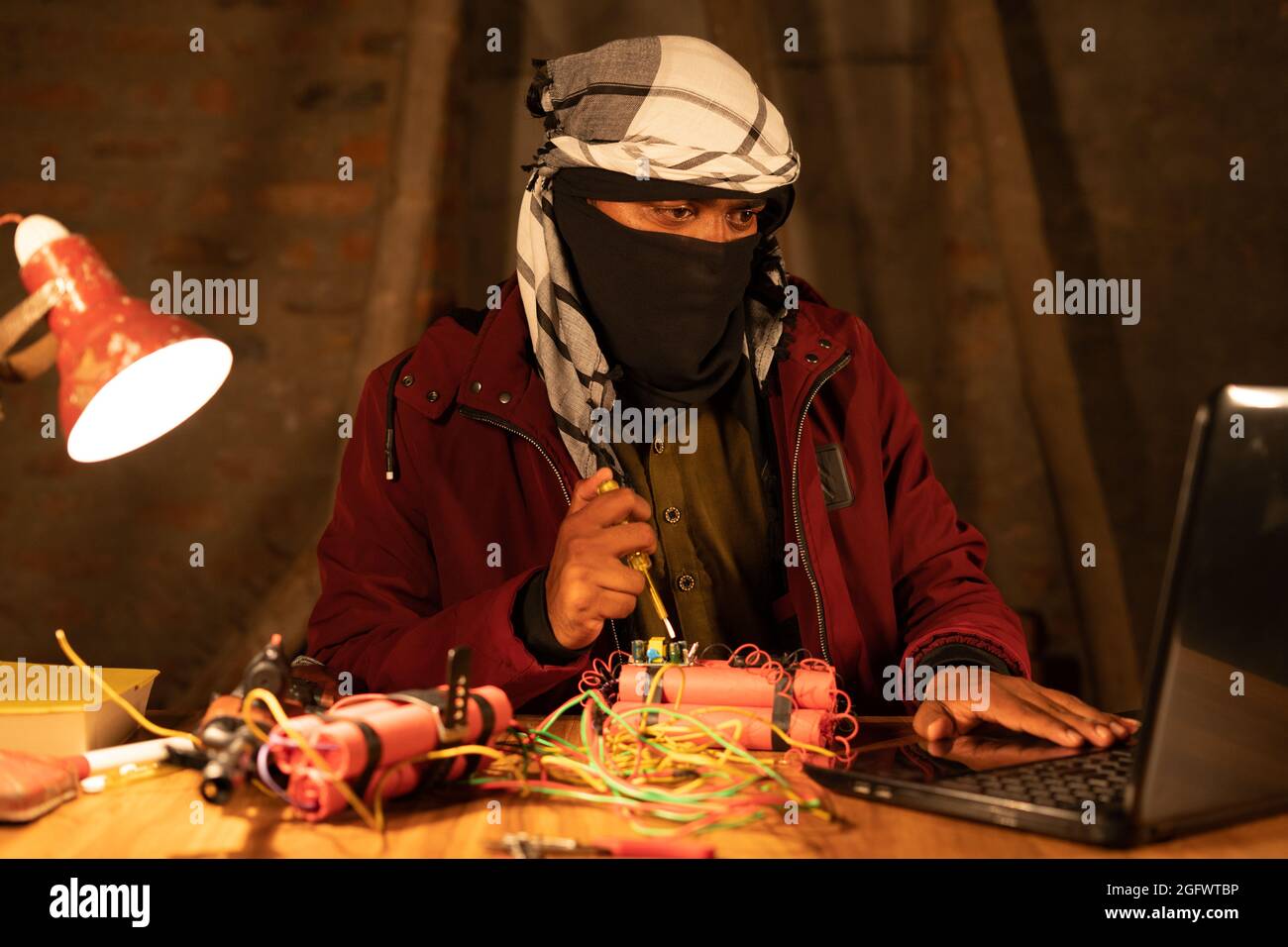 Militante con copertina apprendimento timer bomba fare con Dynamite guardando nel notebook. Foto Stock