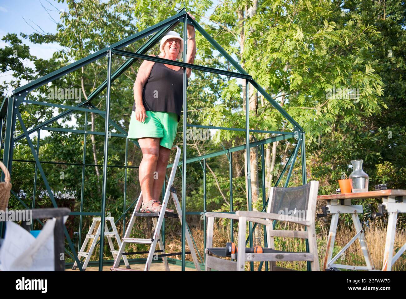 Donna che costruisce serra in giardino Foto Stock