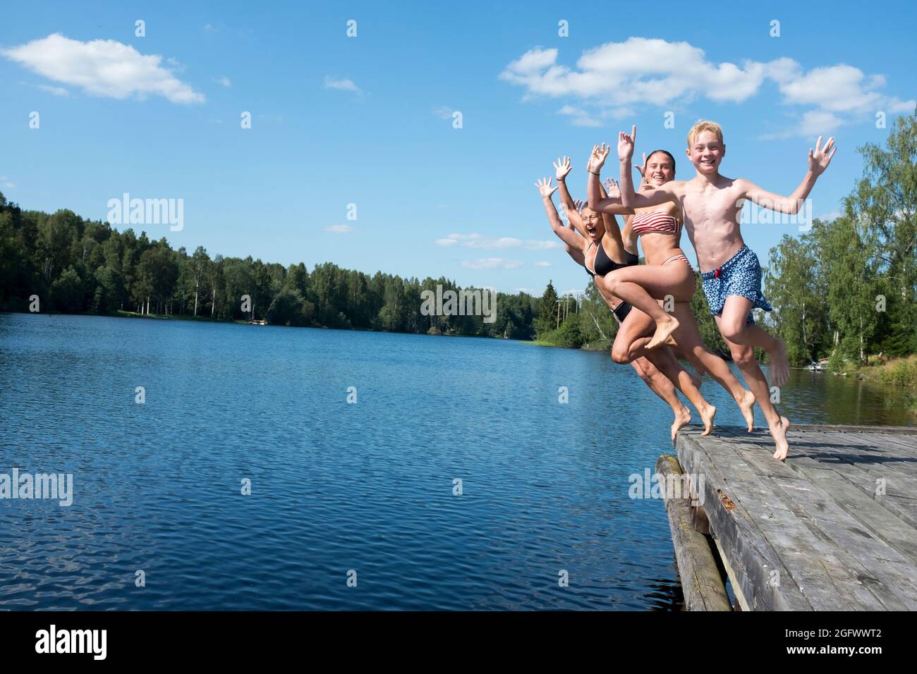 Giovani amici che saltano nel lago Foto Stock