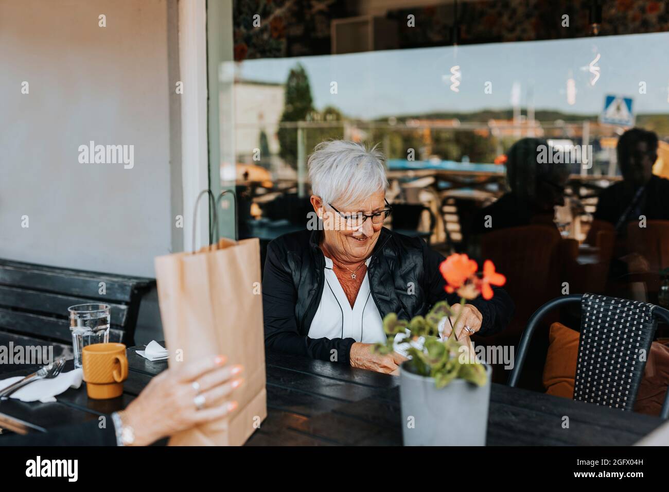 Donna anziana seduta in un bar all'aperto Foto Stock