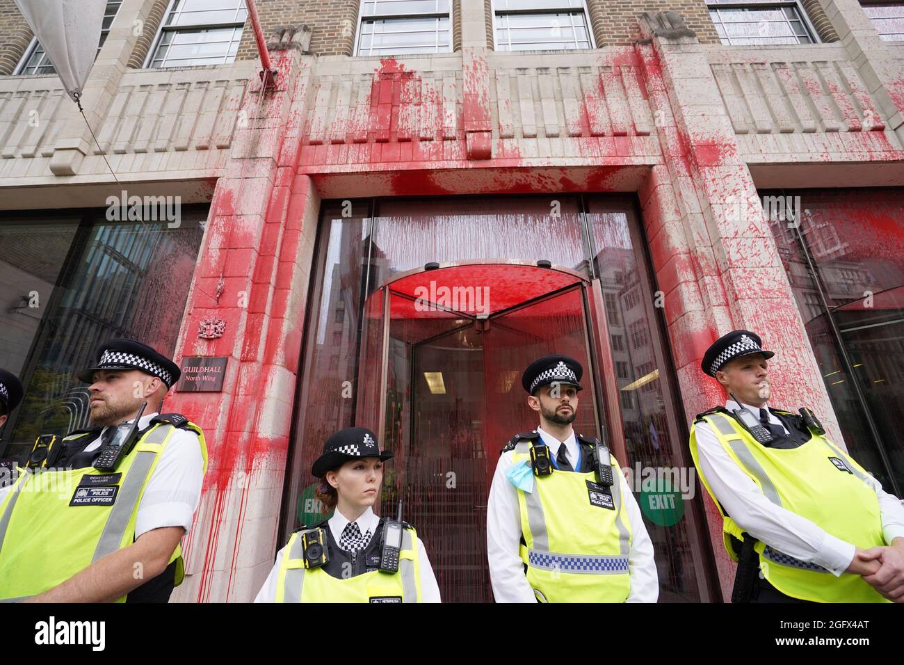 Gli ufficiali di polizia si trovano di fronte a uno degli edifici della Guildhall, che è stato scolorito, mentre una protesta della ribellione dell'estinzione si fa strada attraverso la città di Londra. Data foto: Venerdì 27 agosto 2021. Foto Stock