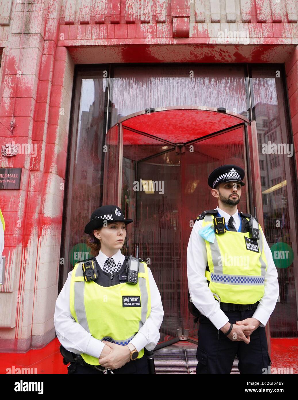 Gli ufficiali di polizia si trovano di fronte a uno degli edifici della Guildhall, che è stato scolorito, mentre una protesta della ribellione dell'estinzione si fa strada attraverso la città di Londra. Data foto: Venerdì 27 agosto 2021. Foto Stock