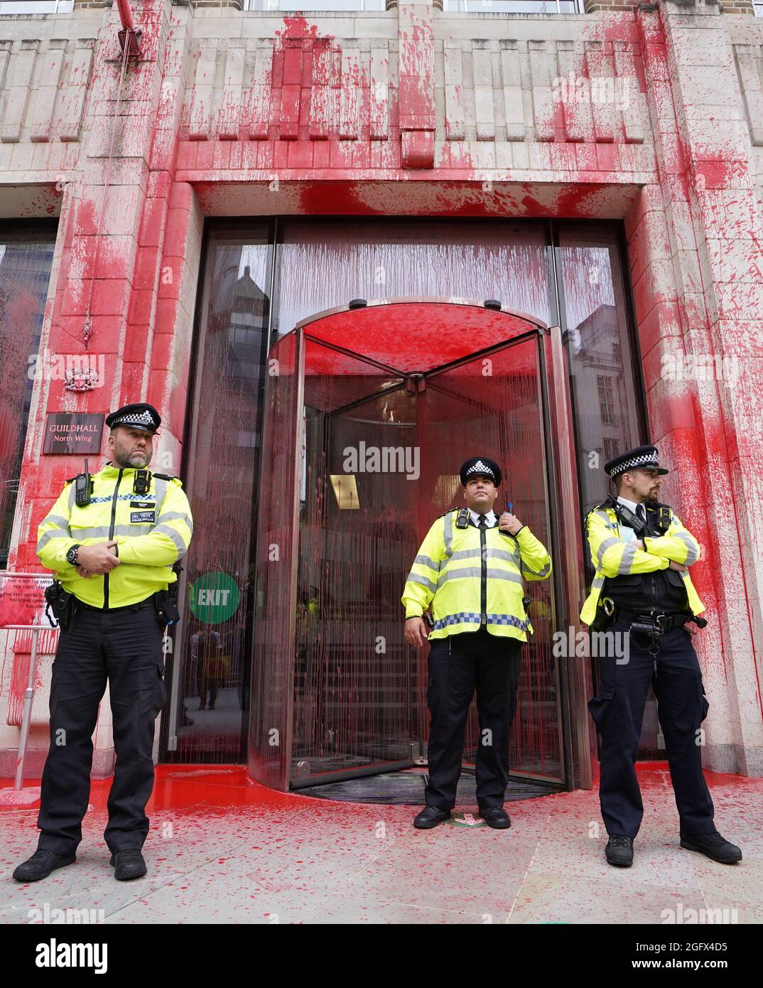 Gli ufficiali di polizia si trovano di fronte a uno degli edifici della Guildhall, che è stato scolorito, mentre una protesta della ribellione dell'estinzione si fa strada attraverso la città di Londra. Data foto: Venerdì 27 agosto 2021. Foto Stock