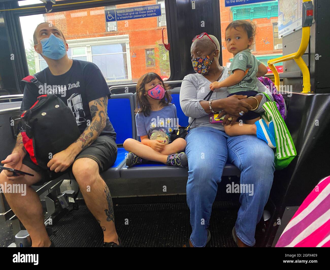 Nanny prendersi cura di fratelli ride autobus vicino a un uomo con molti tatuaggi, Brooklyn, New York. Foto Stock