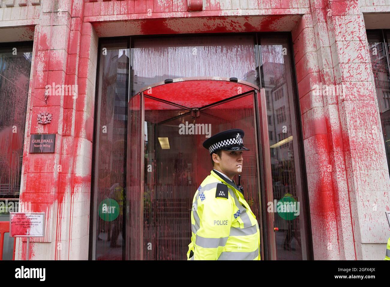 Un ufficiale di polizia si trova di fronte ad uno degli edifici della Guildhall, che è stato scolorito, come una protesta della ribellione di estinzione fa il suo cammino attraverso la città di Londra. Data foto: Venerdì 27 agosto 2021. Foto Stock