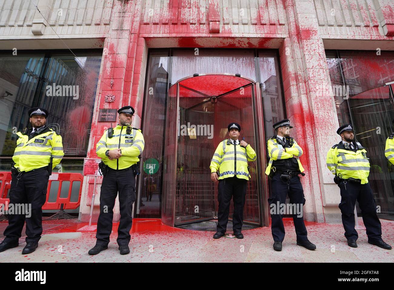 Gli ufficiali di polizia si trovano di fronte a uno degli edifici della Guildhall, che è stato scolorito, mentre una protesta della ribellione dell'estinzione si fa strada attraverso la città di Londra. Data foto: Venerdì 27 agosto 2021. Foto Stock