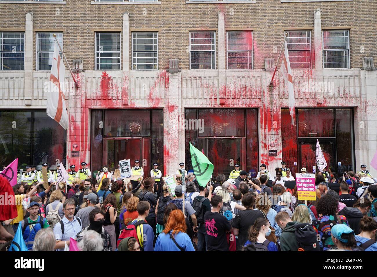 Gli ufficiali di polizia si trovano di fronte a uno degli edifici della Guildhall, che è stato scolorito, mentre una protesta della ribellione dell'estinzione si fa strada attraverso la città di Londra. Data foto: Venerdì 27 agosto 2021. Foto Stock