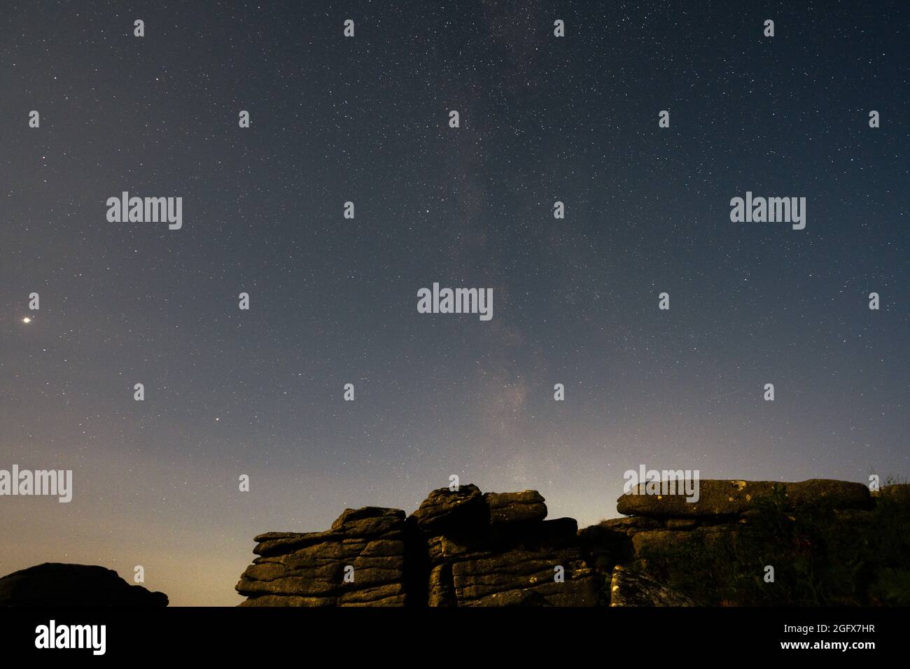 La Via Lattea raffigurata sopra Coombestone Tor su Dartmoor con Giove che fa un aspetto a sinistra Foto Stock