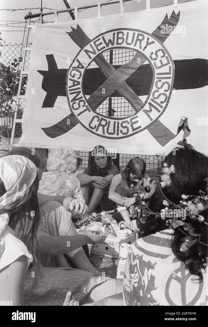1981. Campo comune di pace di Greenham. Donne sedute alla recinzione perimetrale con un grande banner 'Newbury contro i missili della crociera'. Foto Stock
