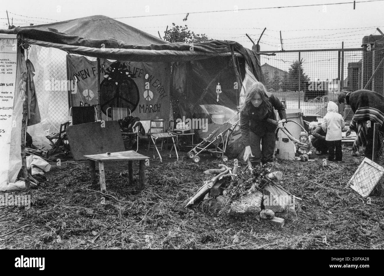 Vita quotidiana al Greenham Common Peace Camp, porta principale, ottobre 1981 con bambini, donne, tende; preparare un fuoco aperto per cucinare cibo comune. Foto Stock