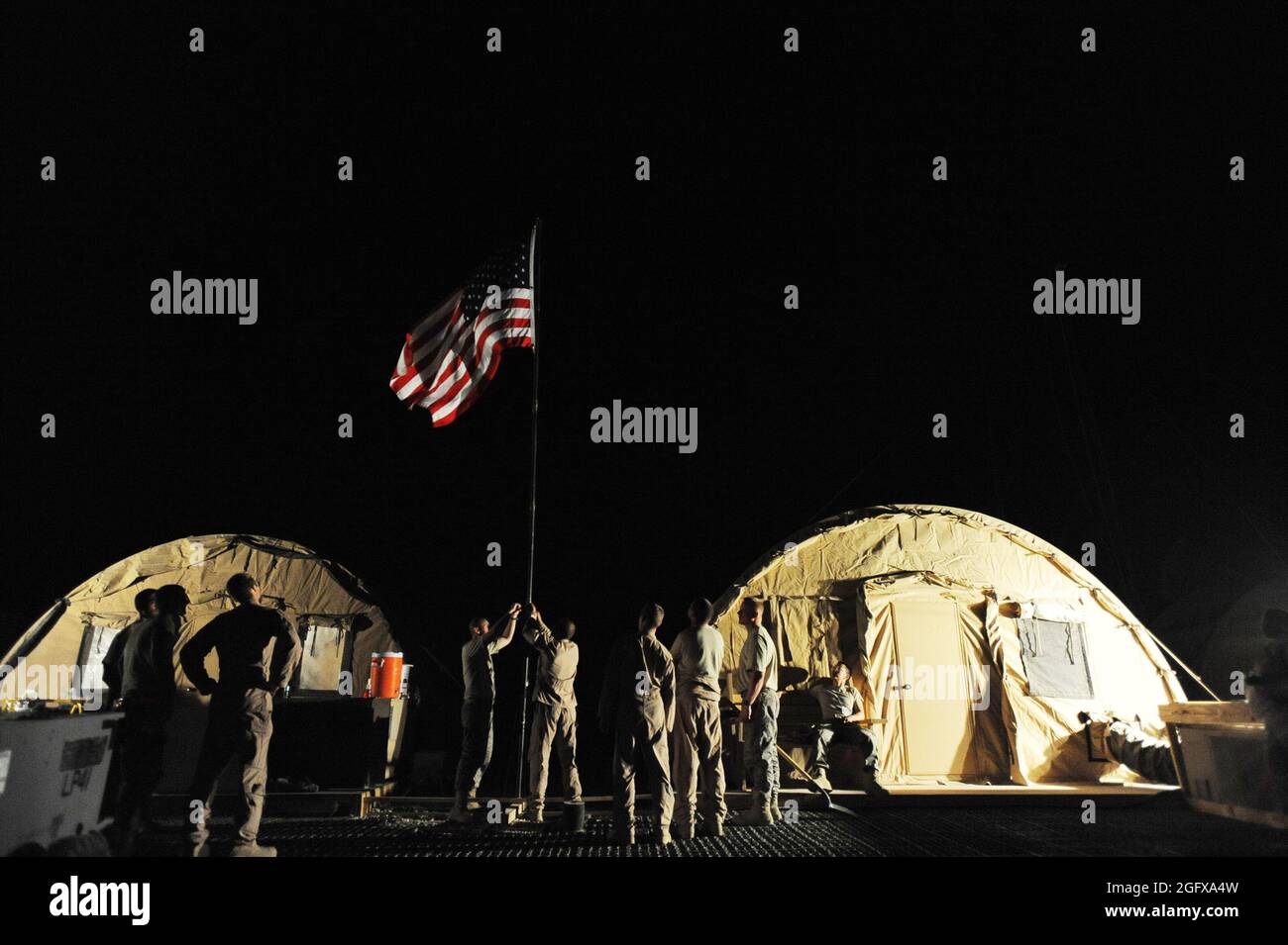 I membri del 79esimo Squadrone di salvataggio Expeditionary assicurano la bandiera dell'unità ad un palo, il 10 aprile, a Camp Bastion, Afghanistan. Con la prima missione di allerta completata, Airmen nello squadrone non vediamo l'ora di un successo di dispiegamento, mostrando allo stesso tempo le capacità uniche del velivolo HC-130P "Combat King". Foto Stock