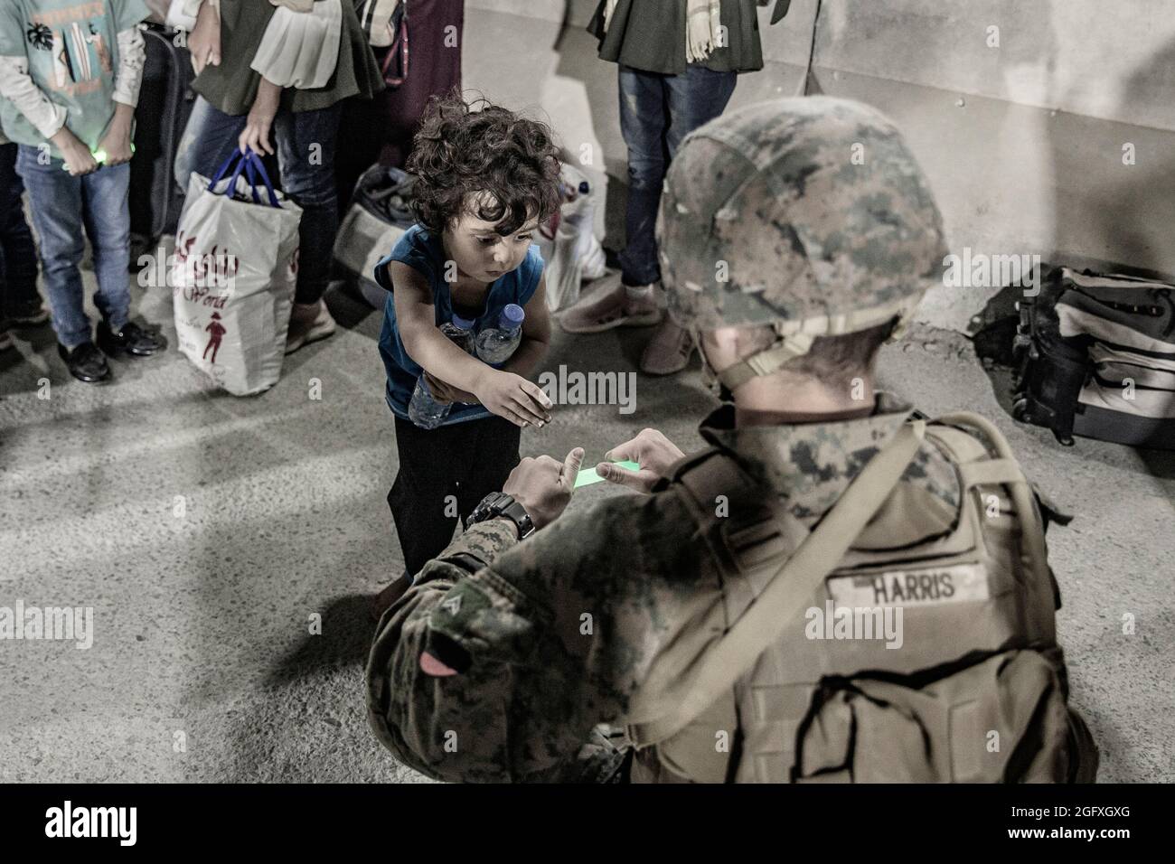 Una Marina statunitense con la 24a unità di spedizione marina (MEU) dà a un bambino una chem light con cui giocare durante un'evacuazione all'aeroporto internazionale Hamid Karzai, Kabul, Afghanistan, 25 agosto. I membri del servizio degli Stati Uniti stanno assistendo il Dipartimento di Stato con un'operazione di evacuazione non combattente (NEO) in Afghanistan. (STATI UNITI Foto del corpo marino di staff Sgt. Victor Mancilla) Foto Stock