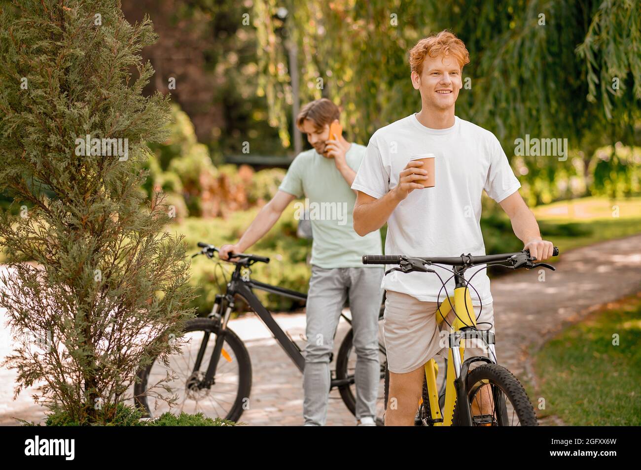 Due ciclisti in piedi all'aperto durante la pausa caffè Foto Stock