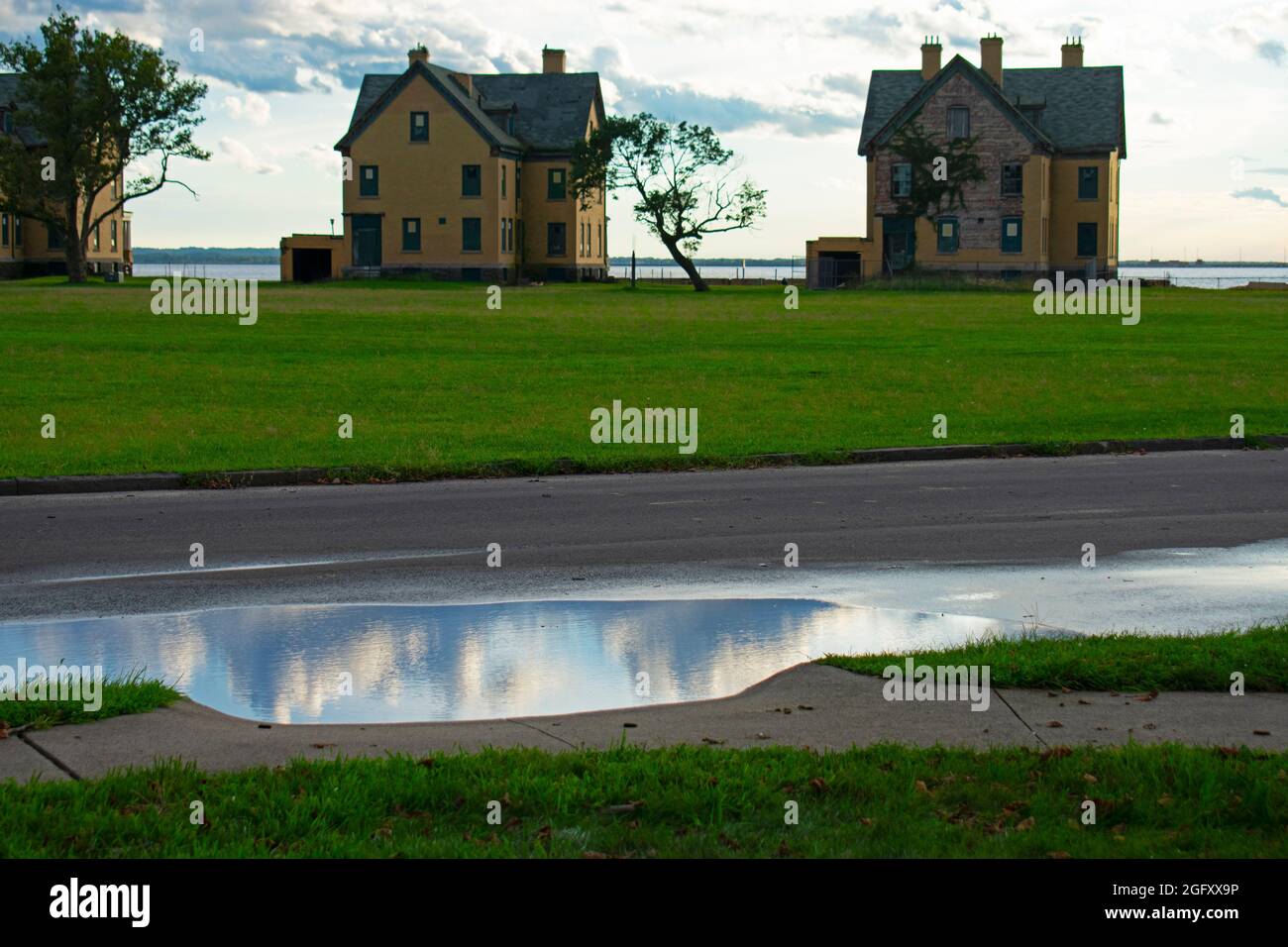 Sagome delle case di Officer's Row a Sandy Hook, New Jersey, dopo una tempesta di pioggia estiva con le pittoresche nuvole riflesse nelle pozzanghere -36 Foto Stock