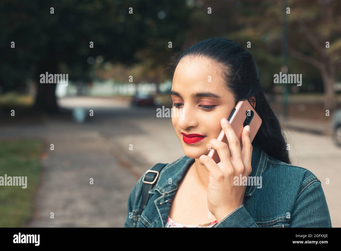 Giovane latino femmina che parla al telefono e sorride Foto Stock