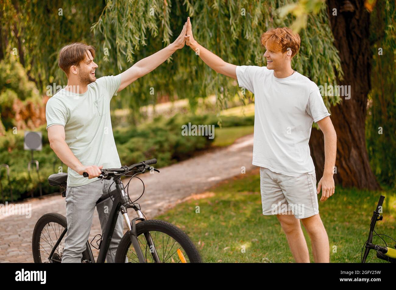 Bicyclist che dà un high-five al suo amico ginger-haired Foto Stock