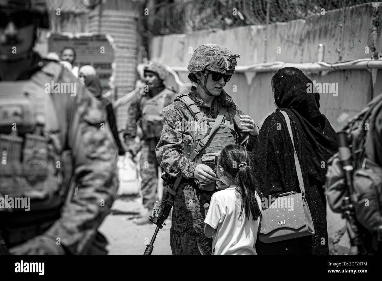 Una Marina assiste una donna e un bambino durante un'evacuazione all'Aeroporto Internazionale Hamid Karzai, 18 agosto. I membri del servizio degli Stati Uniti stanno assistendo il Dipartimento di Stato con un prelievo ordinato di personale designato in Afghanistan. (STATI UNITI Foto del corpo marino di 1° Ora. Mark Andries) Foto Stock