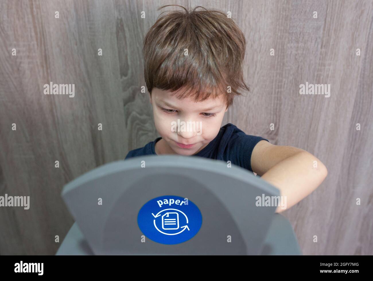 Bambino ragazzo gettando carta per lo spreco di bidone per la carta a casa. Formazione sul concetto di segregazione dei rifiuti Foto Stock
