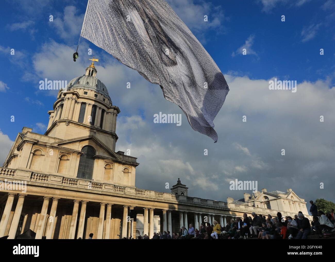 Greenwich, Londra, Regno Unito. 27 ago 2021. "We are watching" di Dan Acher viene lanciato oggi come parte del Greenwich and Docklands International Festival. La bandiera gigante è un occhio monumentale, composto da migliaia di ritratti provenienti da 190 paesi. Vola in alto sopra i giardini e lo splendido edificio dello storico Old Royal Naval College. Credit: Imagplotter/Alamy Live News Foto Stock