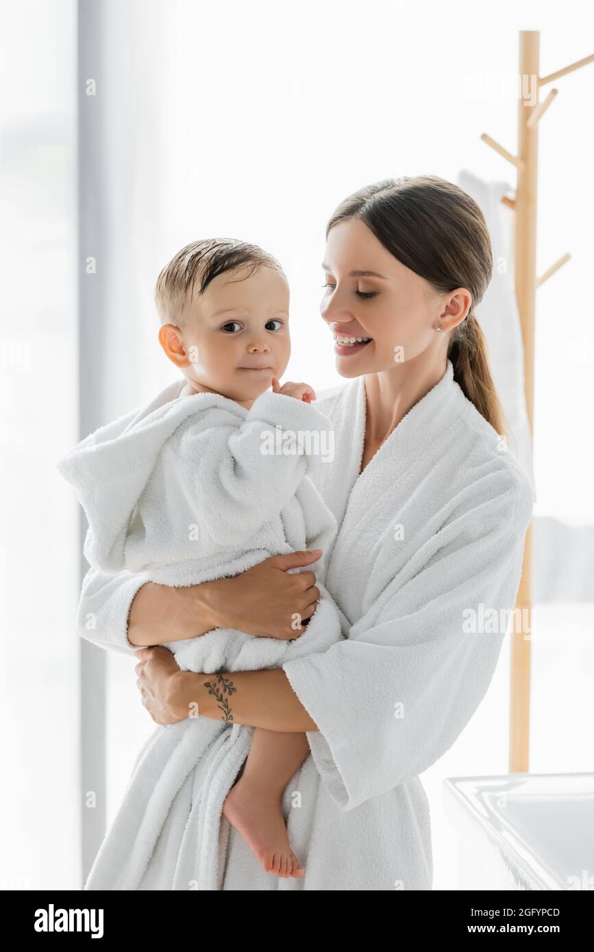 felice madre che guarda il bambino in accappatoio Foto Stock