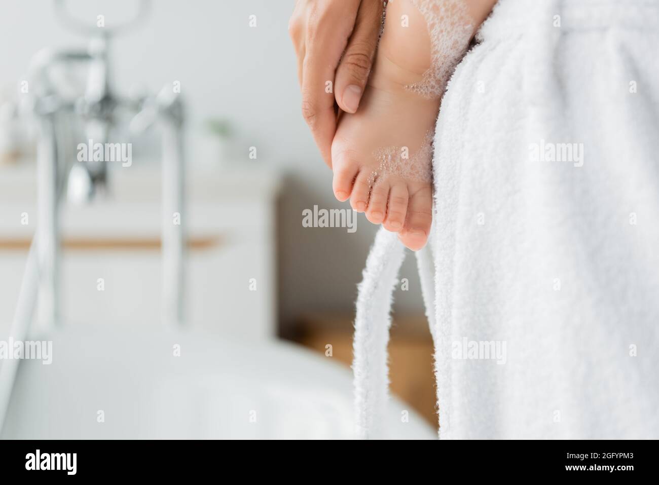 vista croppata della madre che tiene il figlio del toddler nella stanza da bagno Foto Stock