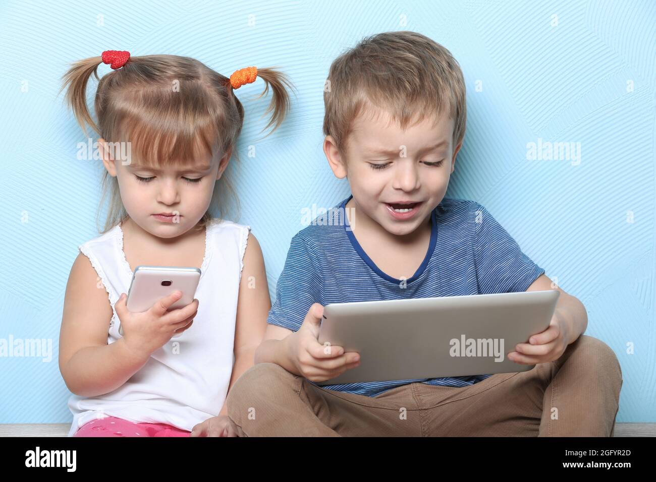 Simpatici e divertenti bambini con tablet e telefono cellulare su sfondo a  colori Foto stock - Alamy