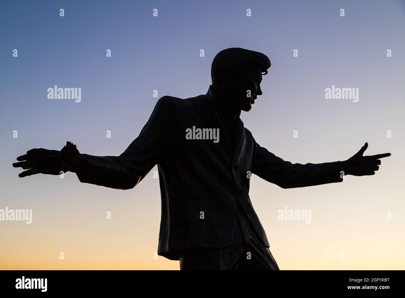 La statua di Billy Fury sul lungomare di Liverpool si staglia contro il tramonto del sole visto nell'agosto 2021. Foto Stock