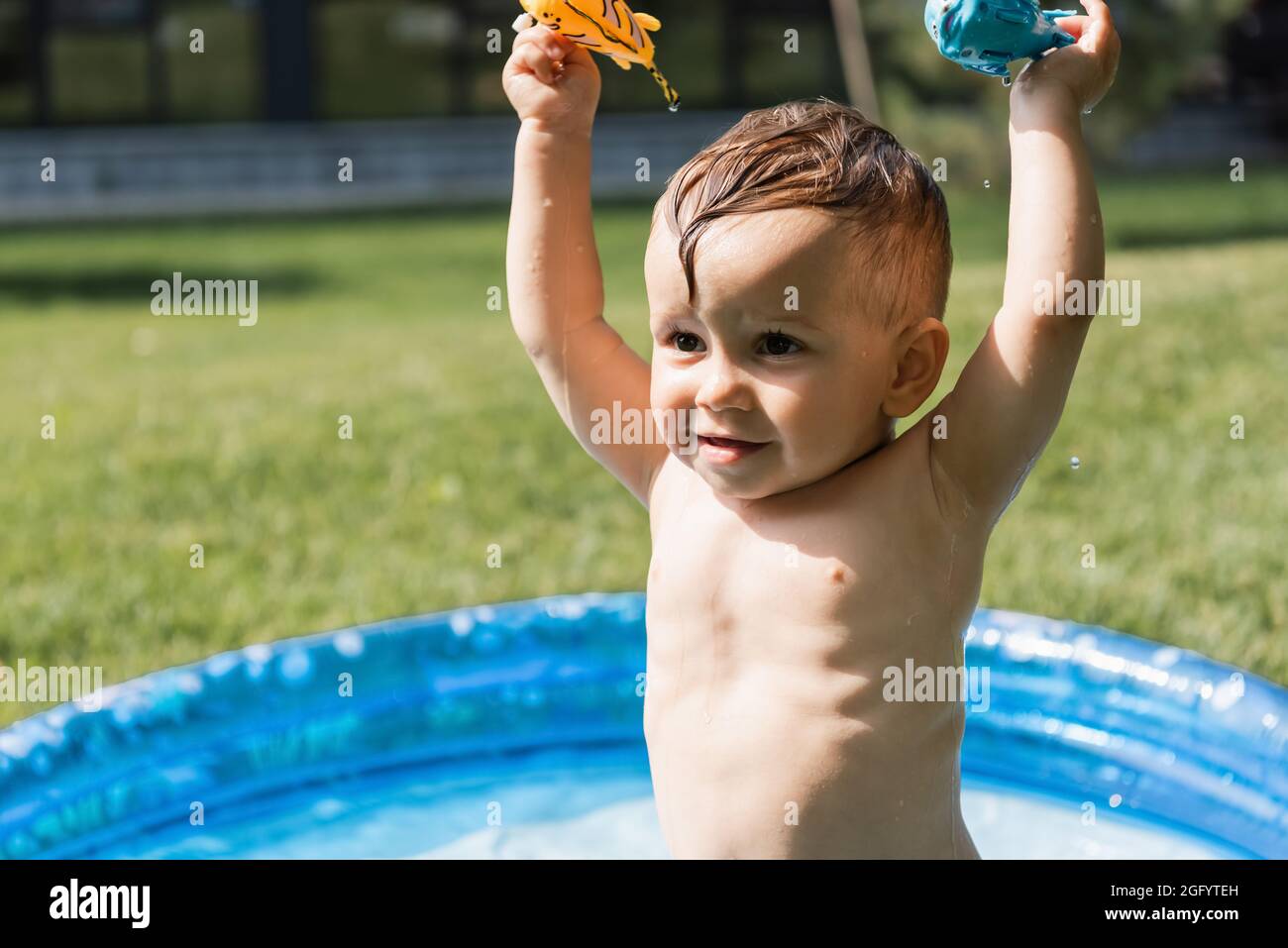 ragazzo allegro toddler che tiene i giocattoli di gomma sopra la testa fuori Foto Stock